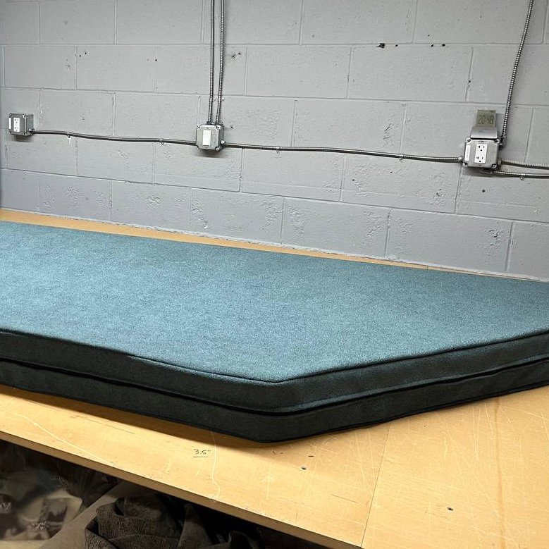 Craftsman using a spray gun to apply a finish to a wooden surface in a workshop environment.